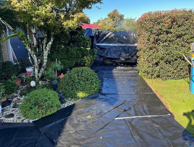 A Black Tarp Is Covering a Driveway in A Garden — Northern Rivers Demolition & Asbestos in Grafton, NSW