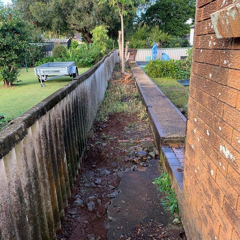 A Dirt Path Leading to A Brick Building Next to A Fence — Northern Rivers Demolition & Asbestos in Ballina, NSW