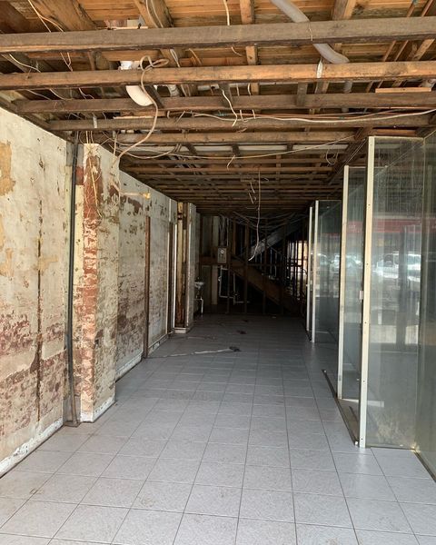 A Long Hallway in A Building with A Wooden Ceiling and Brick Walls A Beach with Waves Crashing on The Shore on A Sunny Day — Northern Rivers Demolition & Asbestos in Murwillumbah, NSW
