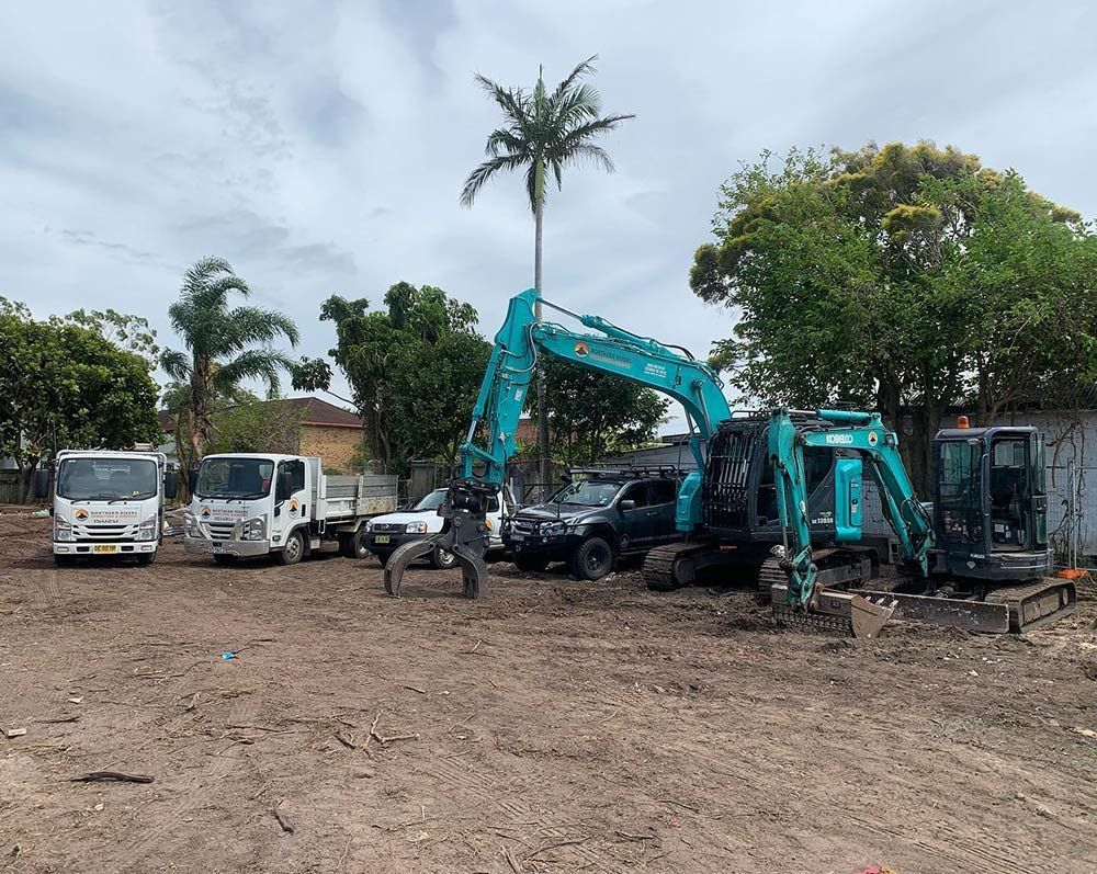 A Group of Construction Vehicles Are Parked in A Dirt Lot — Northern Rivers Demolition & Asbestos in Casino, NSW