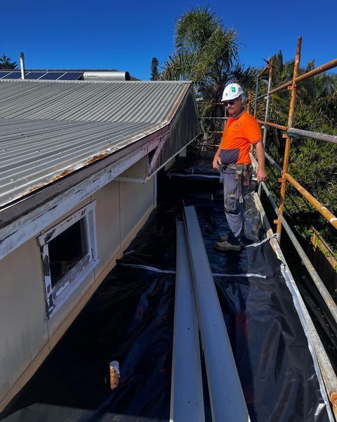 A Man Is Standing on The Roof of A Building — Northern Rivers Demolition & Asbestos in Byron Bay, NSW
