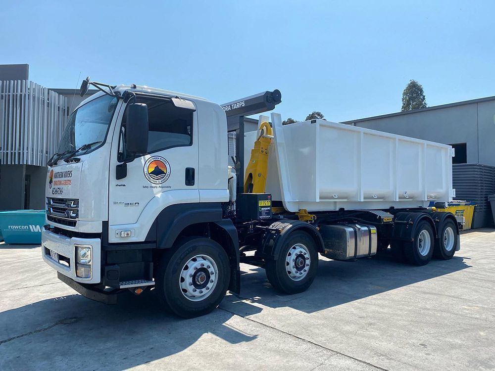 A White Dump Truck with A Yellow Crane Is Parked in A Parking Lot — Northern Rivers Demolition & Asbestos in Skennars Head, NSW