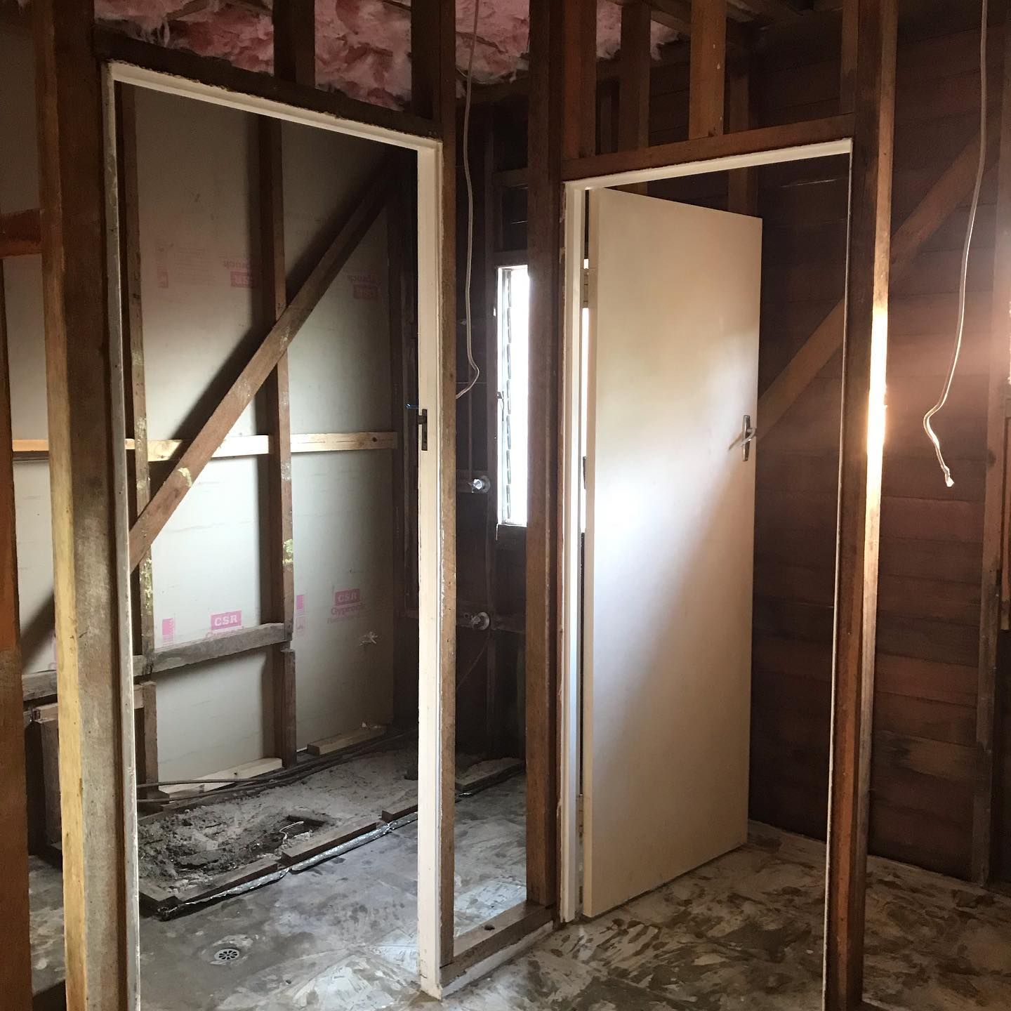 Two White Doors Are Open in A Room with Wooden Walls — Northern Rivers Demolition & Asbestos in Tweed Heads, NSW