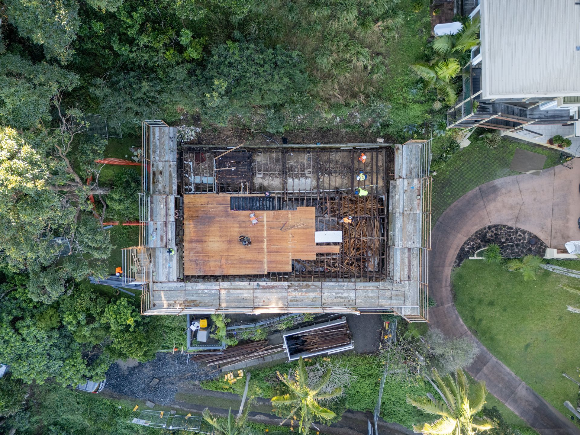 An aerial view of a house under construction in the middle of a forest.