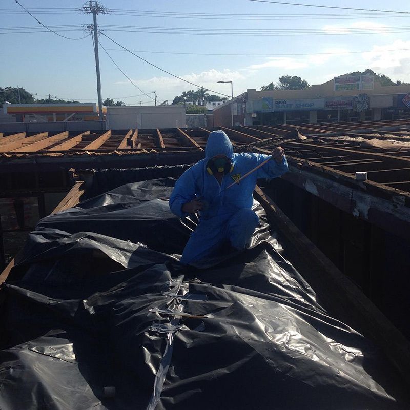 A Man in A Blue Hooded Jacket Is Spraying Something — Northern Rivers Demolition & Asbestos in Casino, NSW
