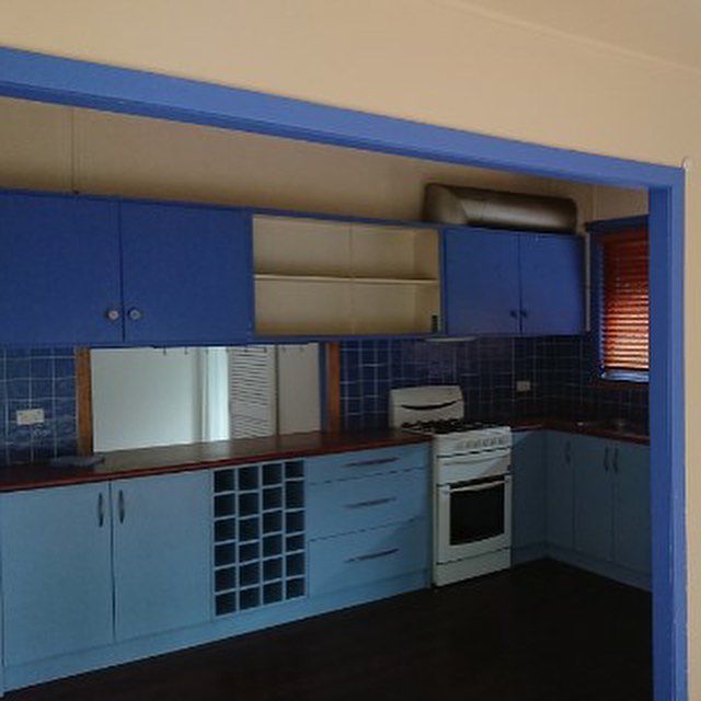 A Kitchen with Blue Cabinets and A White Stove — Northern Rivers Demolition & Asbestos in Tweed Heads, NSW