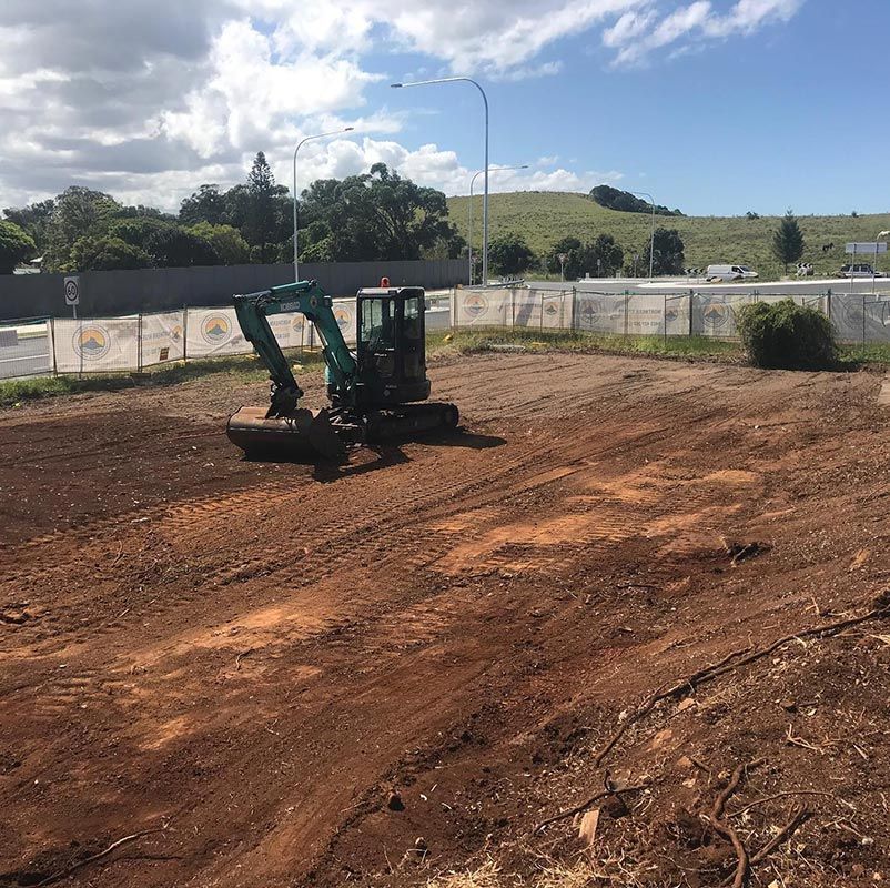 A Green Excavator Is Working in A Dirt Field — Northern Rivers Demolition & Asbestos in Casino, NSW