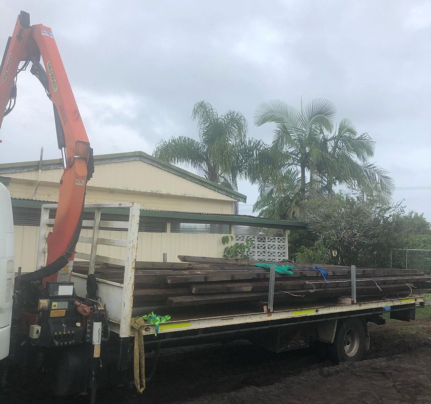 A Truck with A Crane on The Back Is Loaded with Wooden Poles — Northern Rivers Demolition & Asbestos in Ballina, NSW