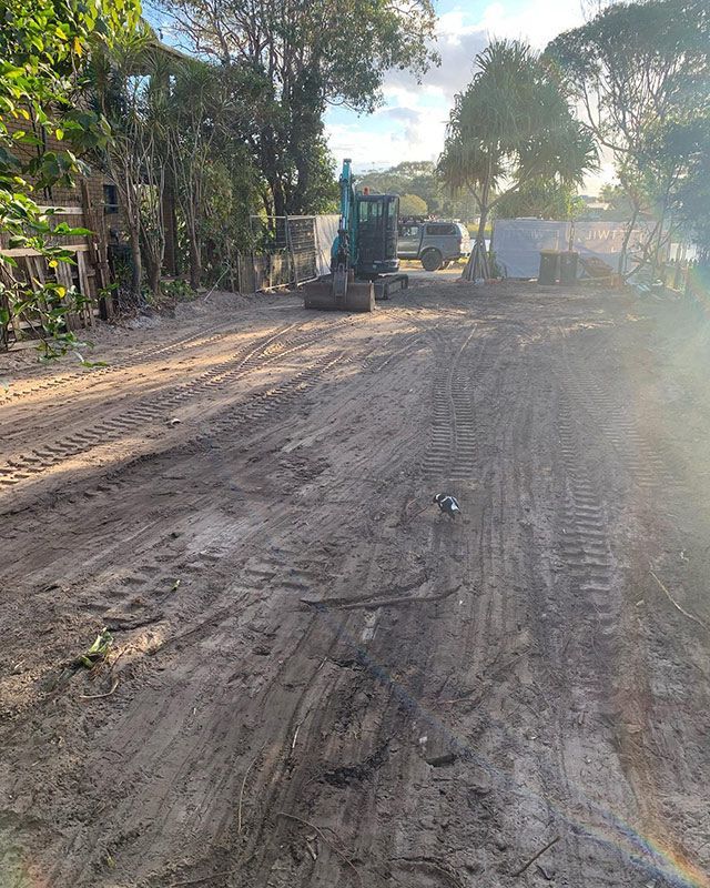 A Bulldozer Is Driving Down a Dirt Road — Northern Rivers Demolition & Asbestos in Tweed Heads, NSW