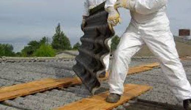 A Man in A White Suit Is Holding a Piece of Wood — Northern Rivers Demolition & Asbestos in Tweed Heads, NSW