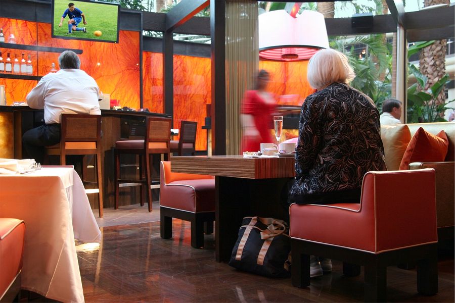 woman sitting down in a restaurant booth with a soccer game playing on the TV in front of her