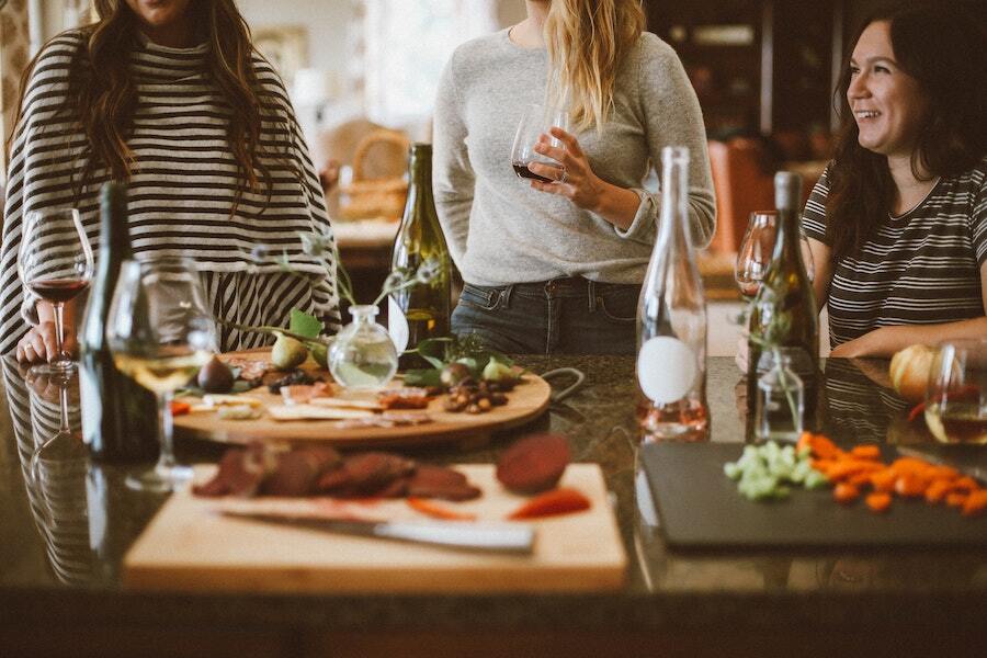 three people standing around a tablet with holiday charcuterie boards and wine glasses