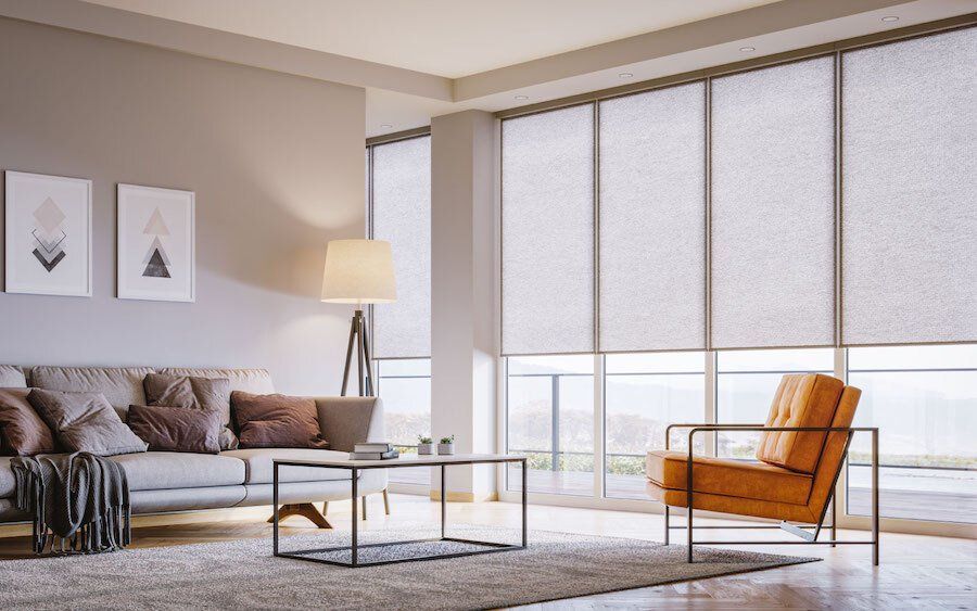 Living room seating area in front of floor-to-ceiling windows with motorized shading solutions from Screen Innovations