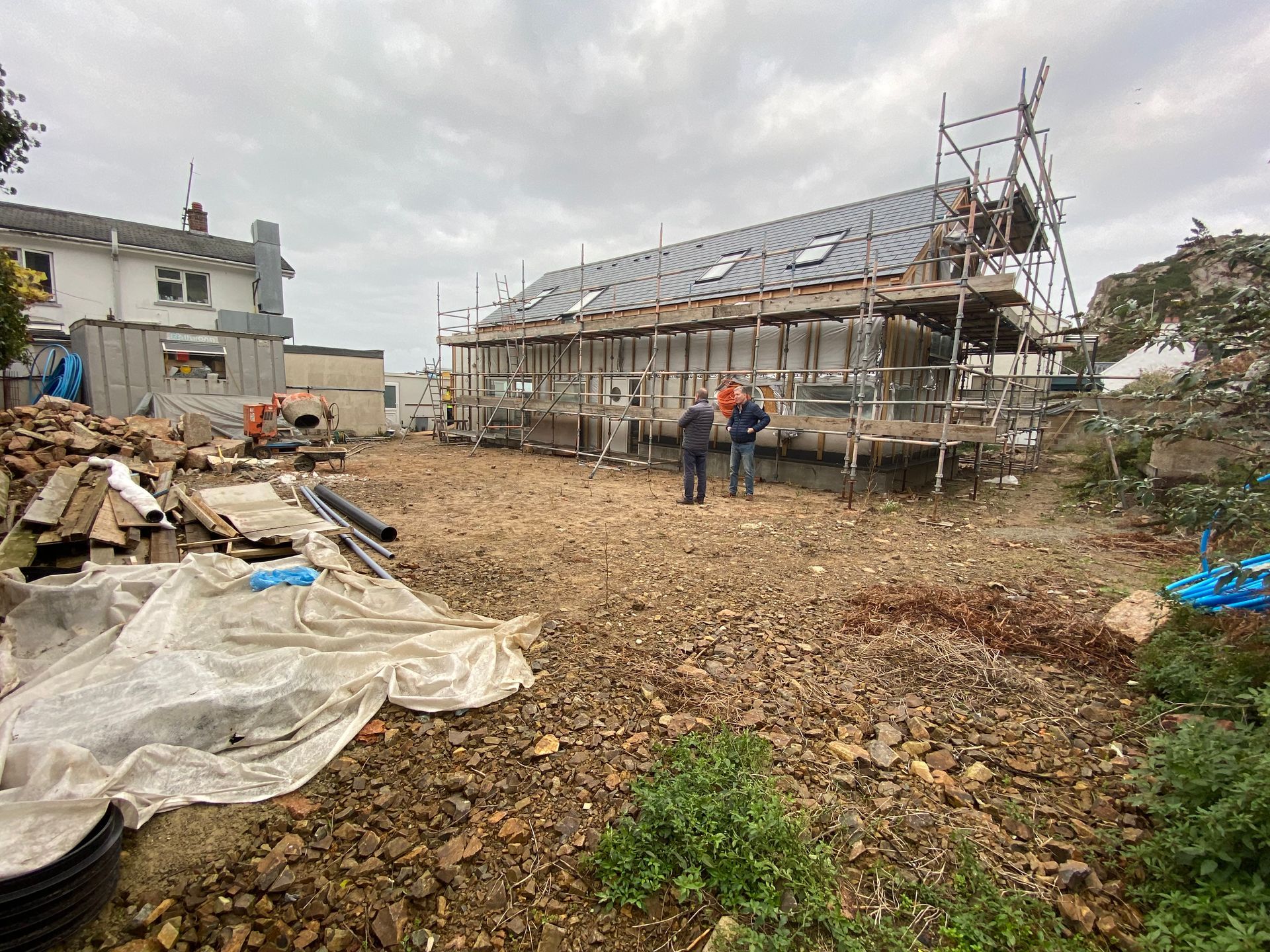 Construction site with a partially built building; three people stand in front.