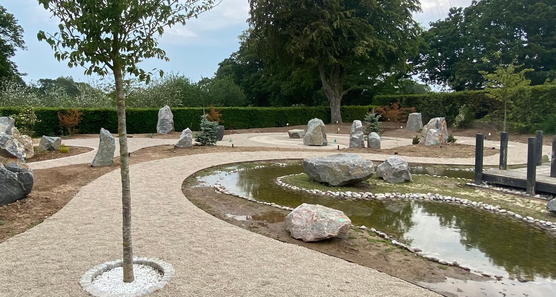 Japanese rock garden with a pond, gravel paths, and mature trees.