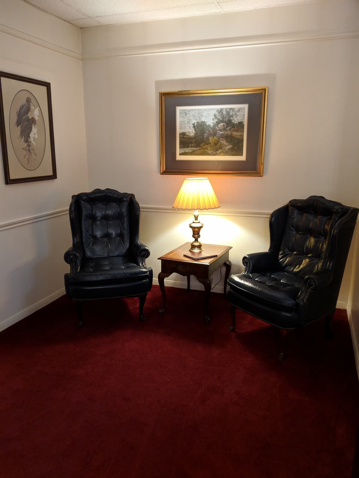 a living room with two chairs a table and a lamp