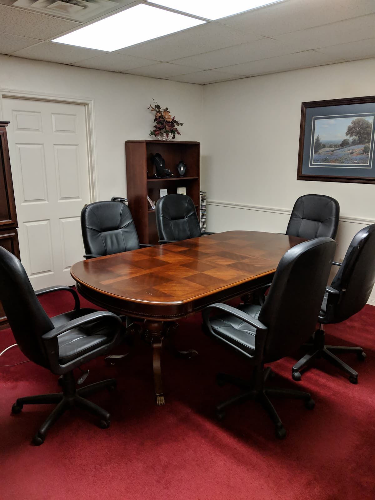 a conference room with a table and chairs and a picture on the wall .