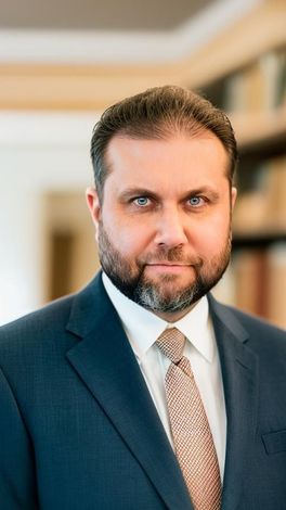 A man with a beard is wearing a suit and tie.