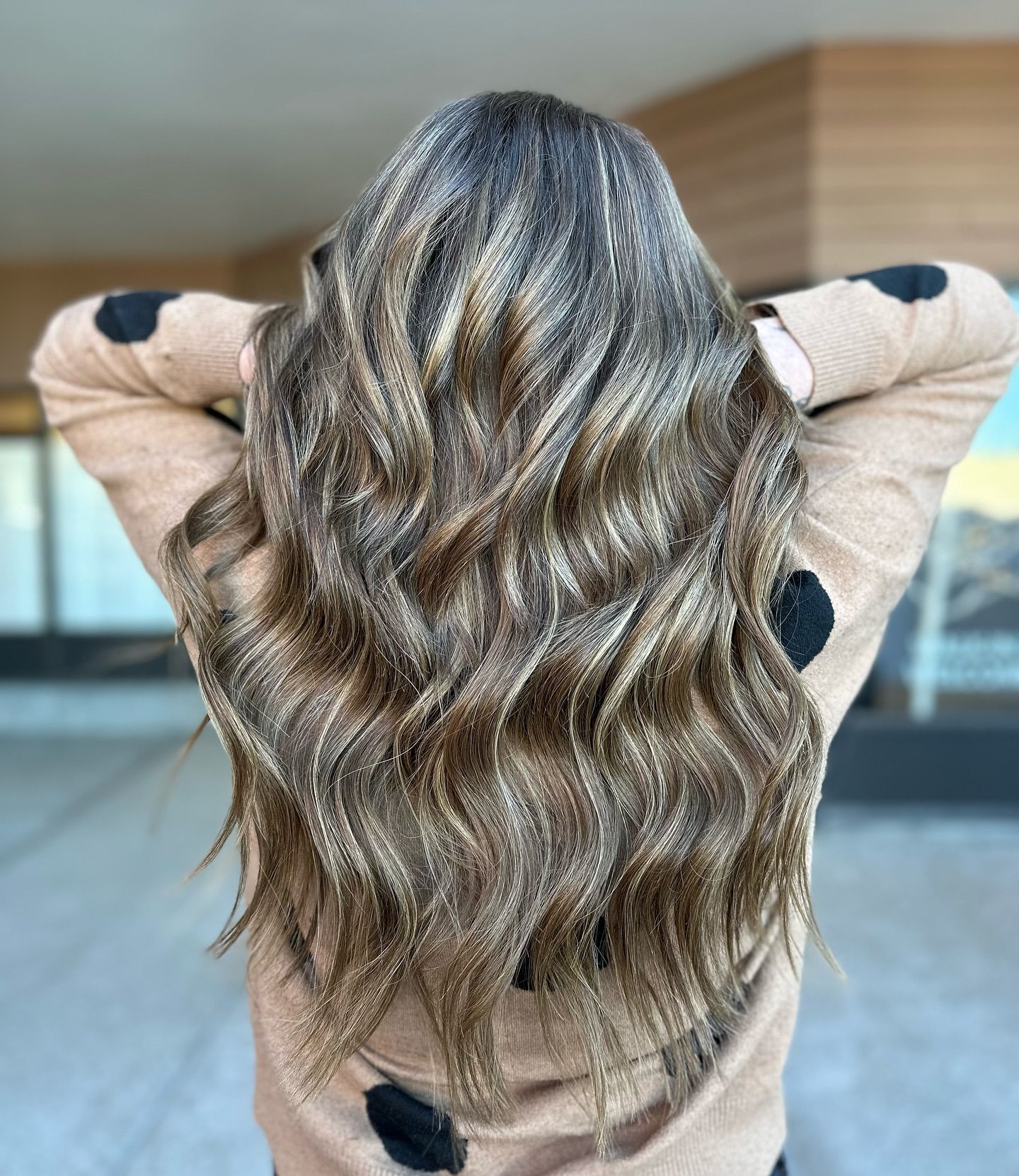A woman with long wavy hair is wearing a polka dot sweater.