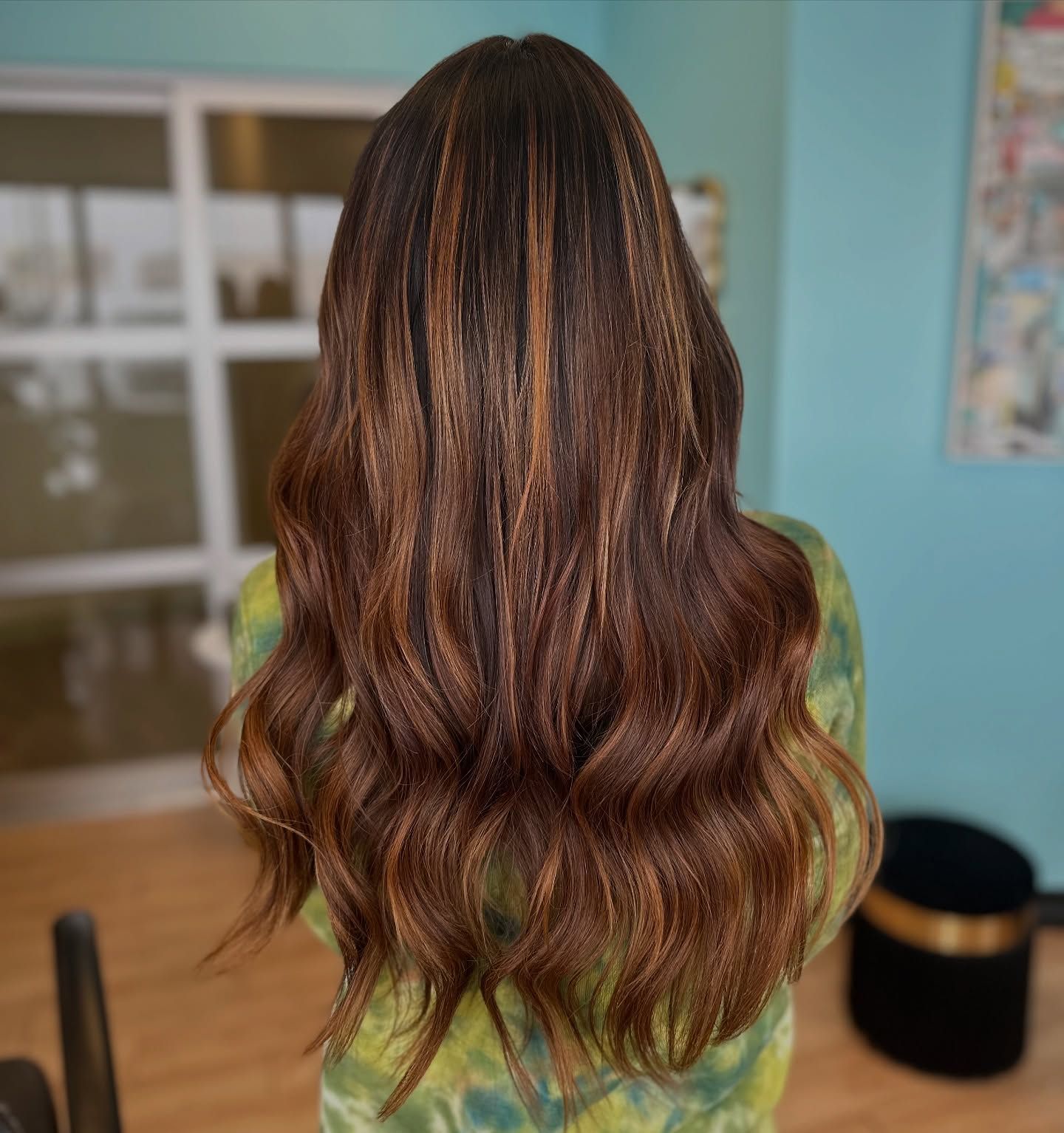 A woman with long brown hair is wearing a green tie dye shirt.