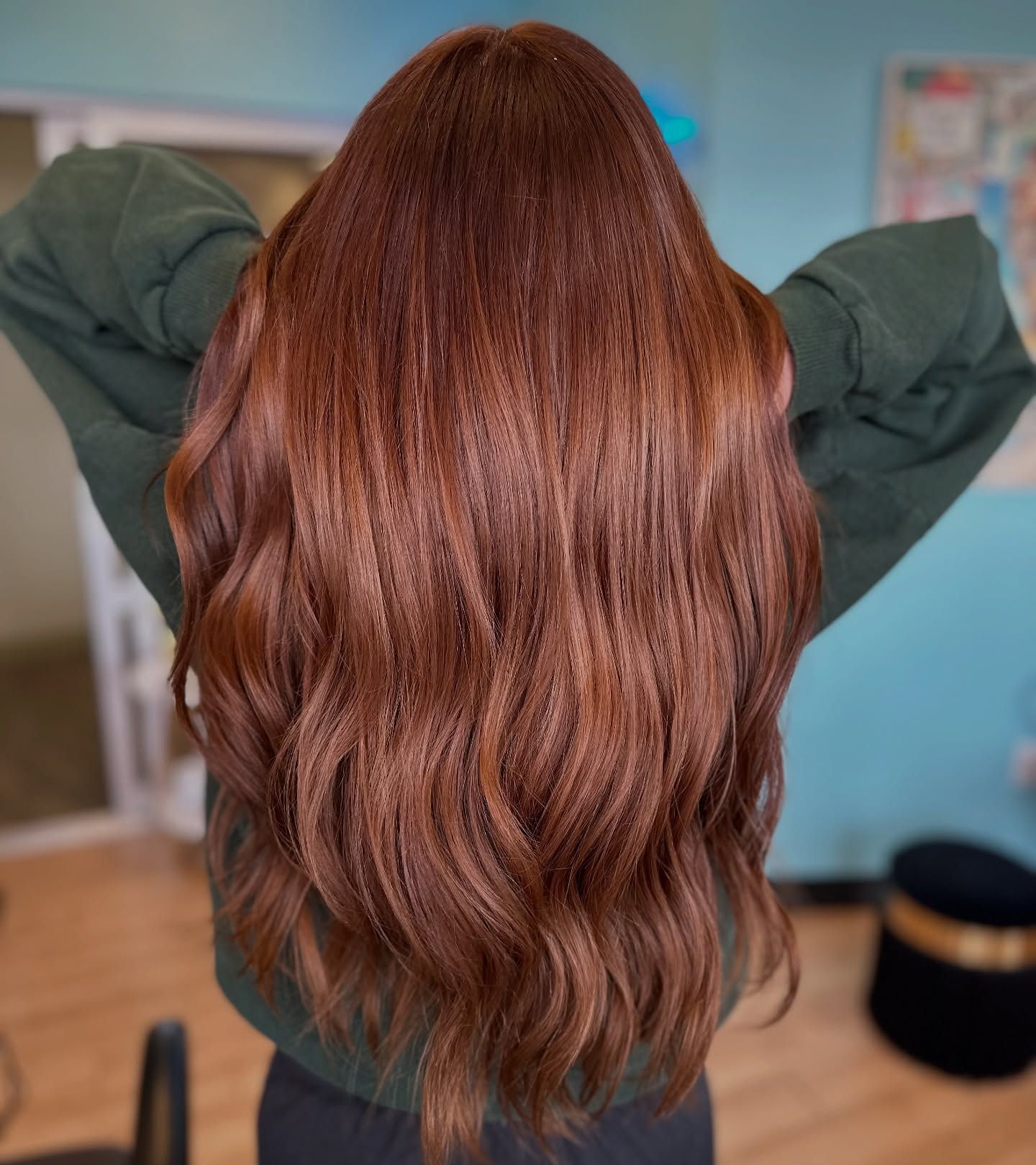 A woman with long brown hair is wearing a green sweater.