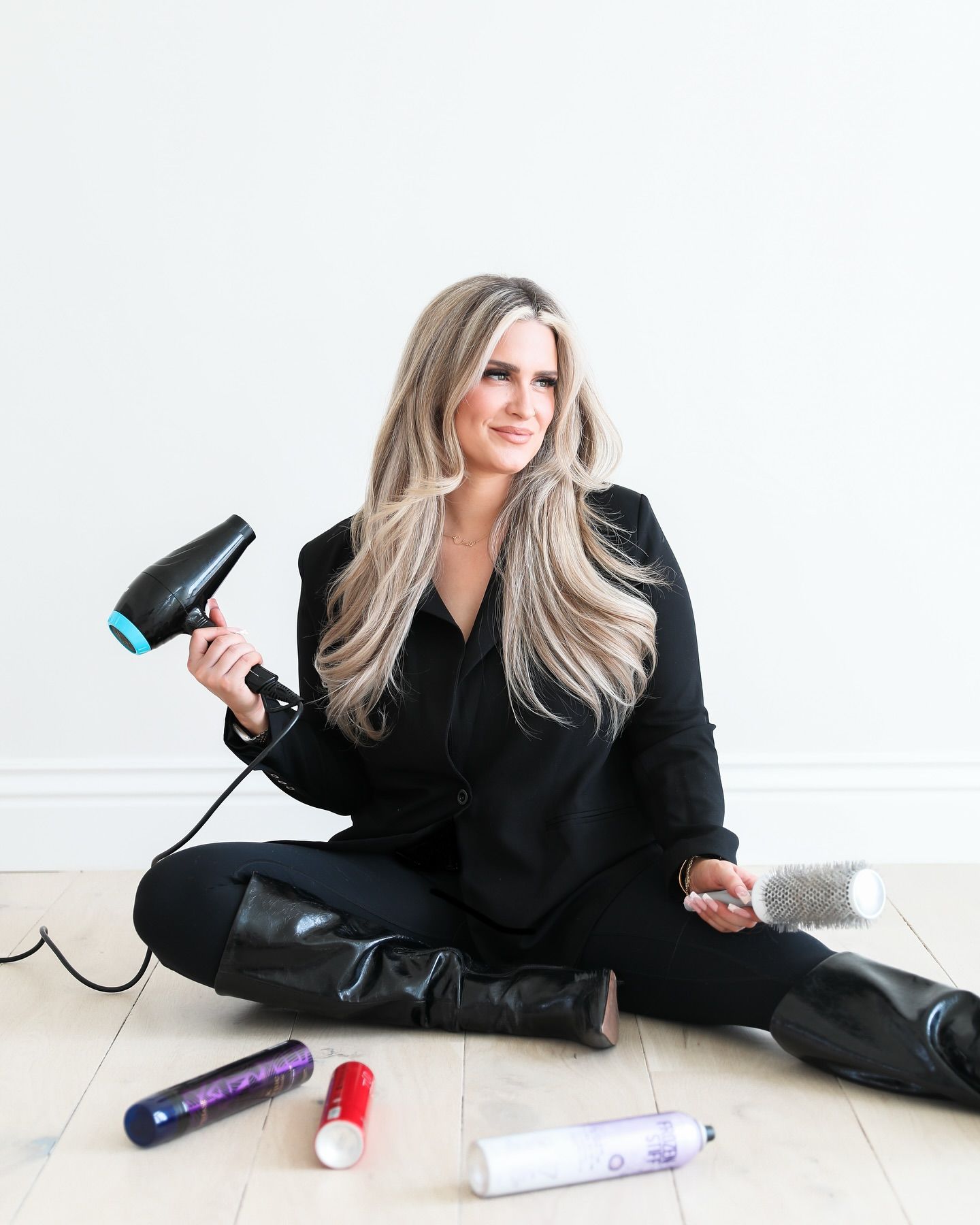 A woman is sitting on the floor holding a hair dryer.