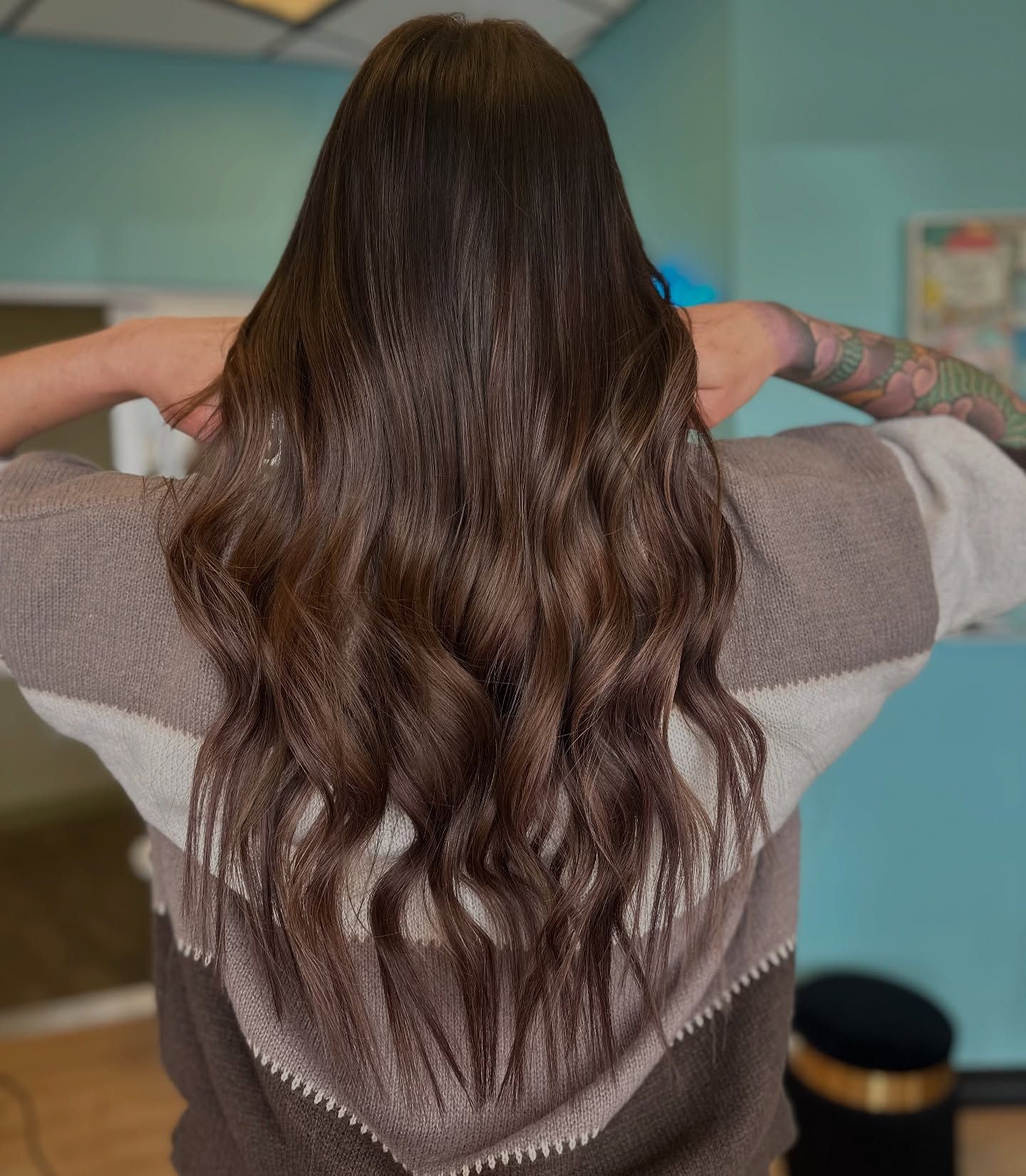 A woman with long brown hair is wearing a sweater.