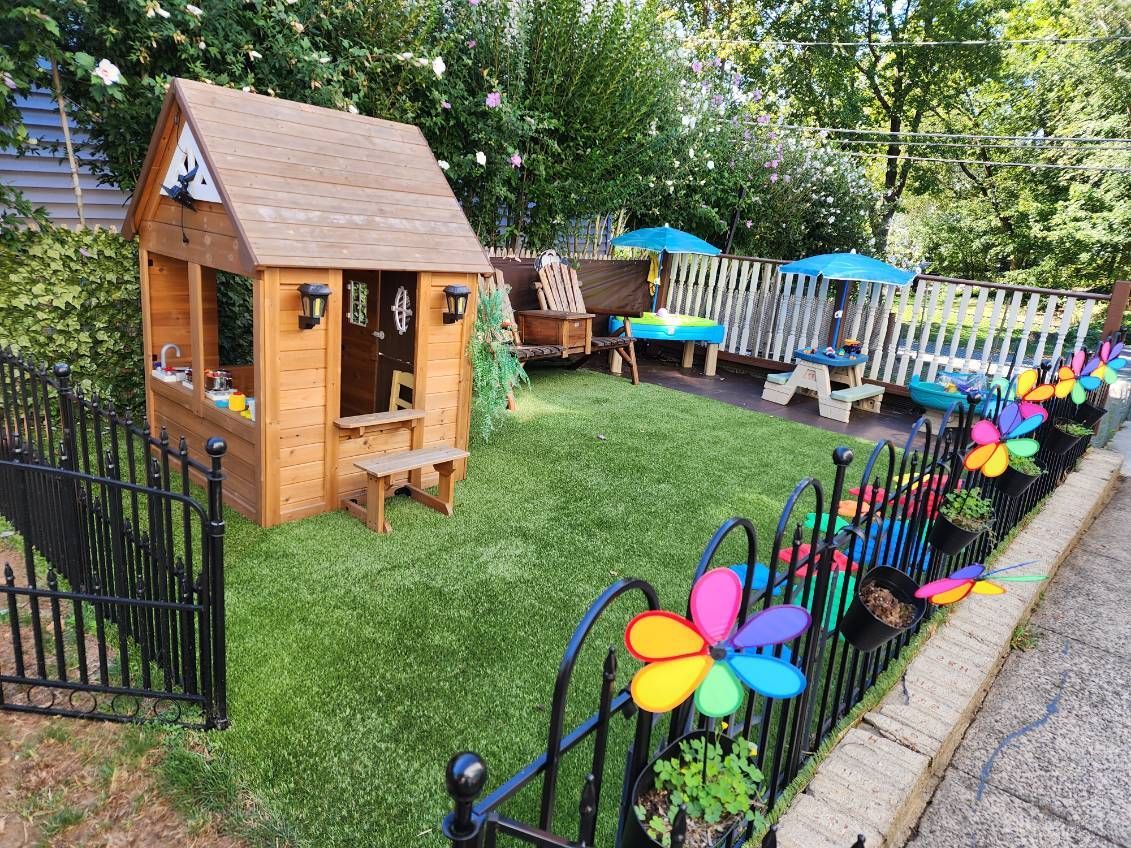 A child's play area with a wooden playhouse, small fence, and colorful decorations.