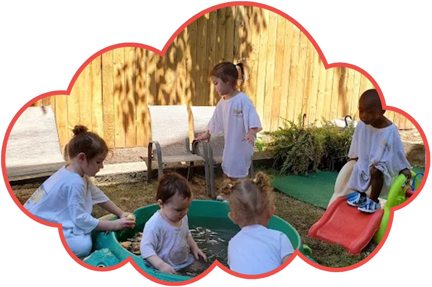 Children playing in a water tub outdoors; wooden fence background.
