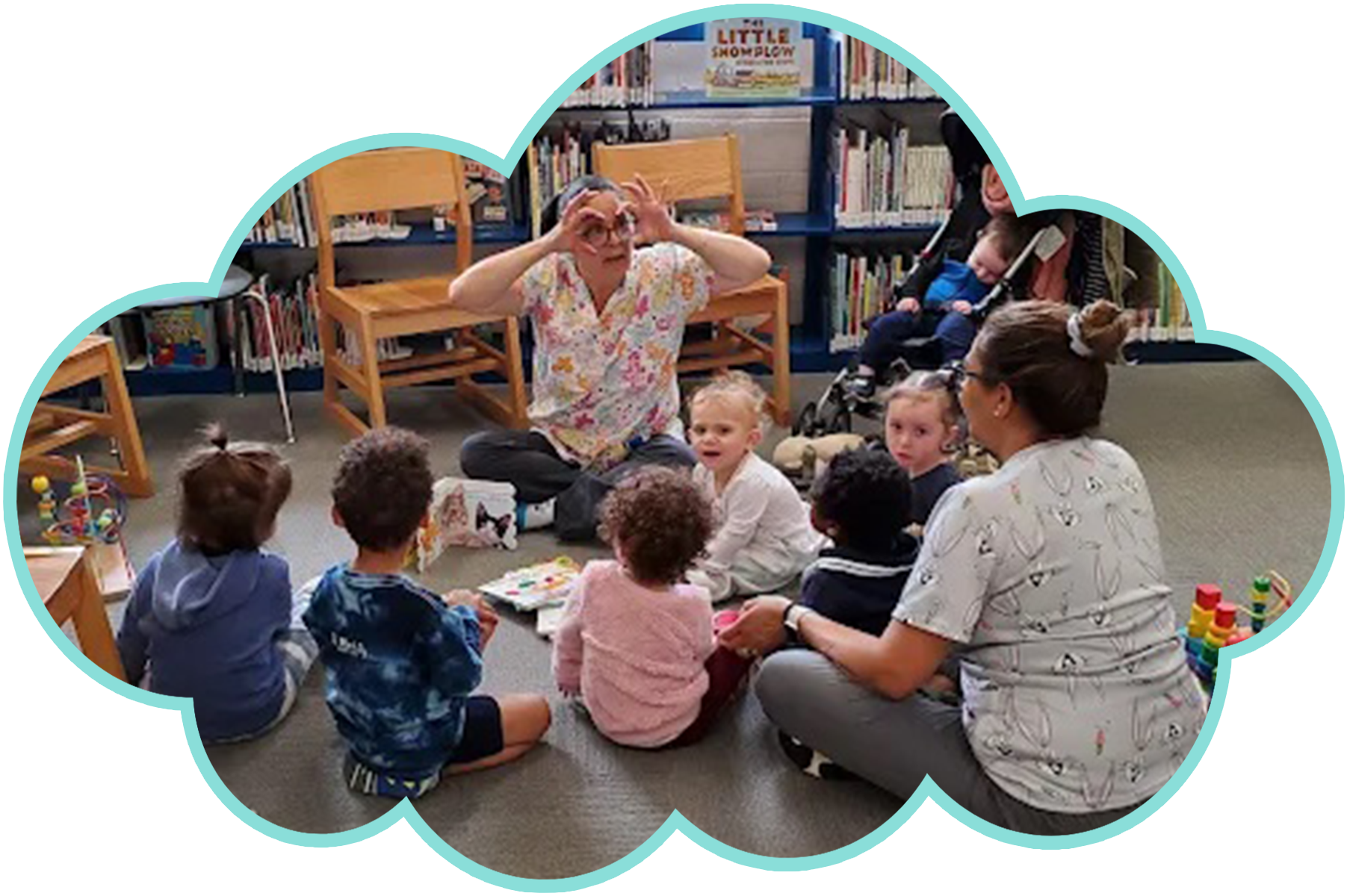 A group of children and adults in a library listen to a story with the storyteller making eye gestures.