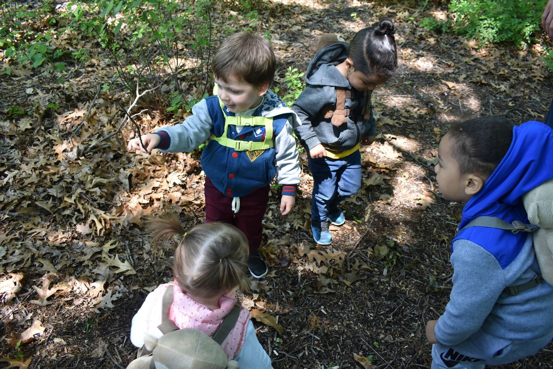 Teacher with three children on a blue rug. They are in a classroom, playing.