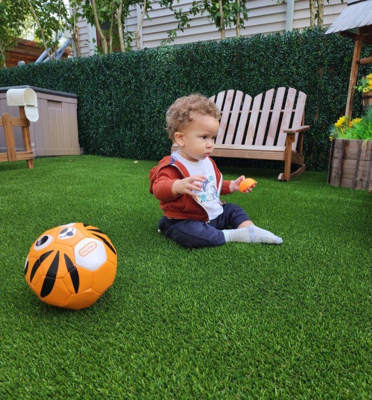 Five young children of diverse races sitting in a classroom, smiling and looking at the camera.
