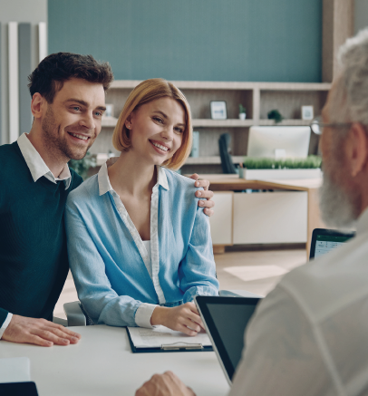 A woman is talking to a man and a woman while sitting at a table with a laptop.