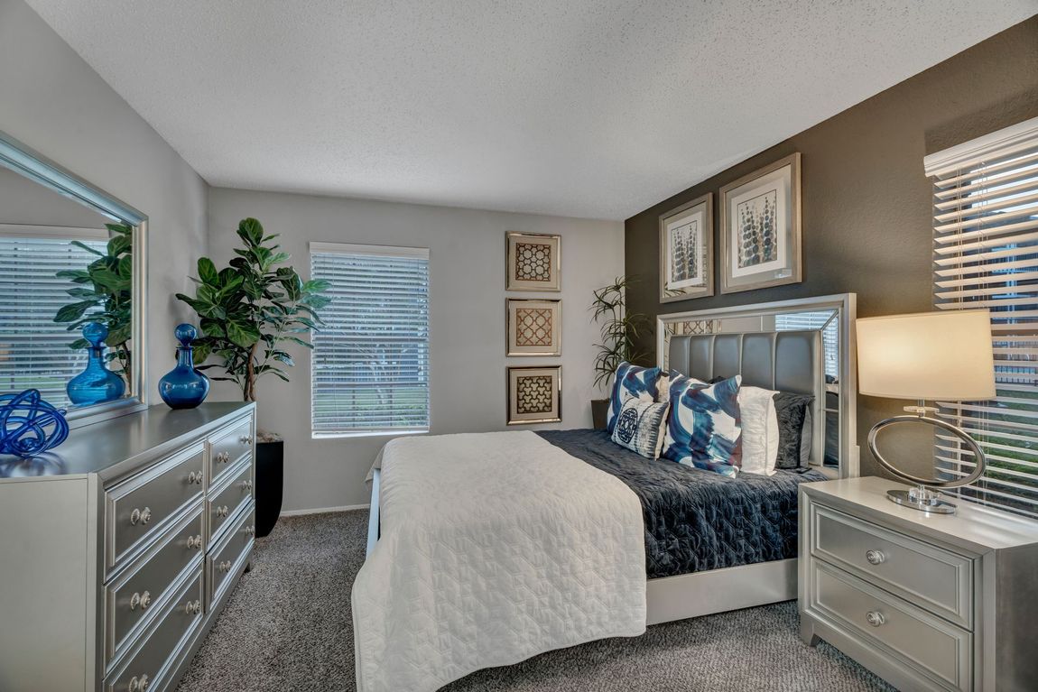 A bedroom with a large bed , dresser , nightstand and mirror.