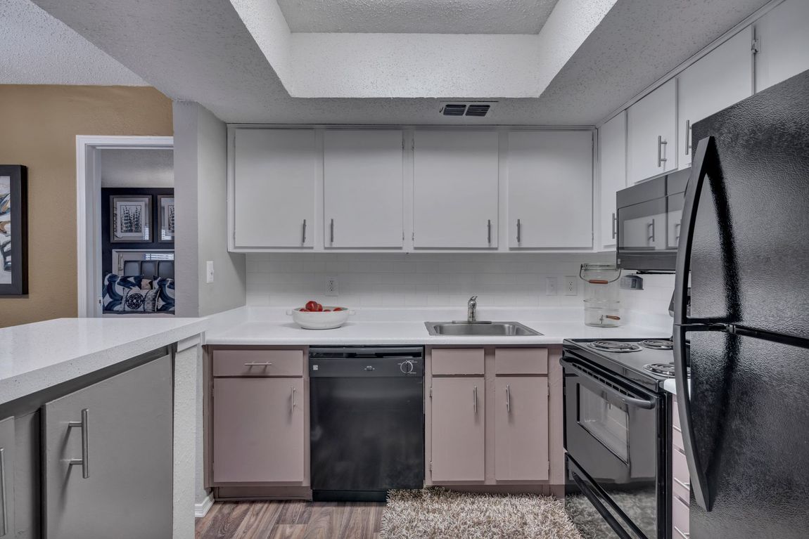 A kitchen with white cabinets and a black refrigerator