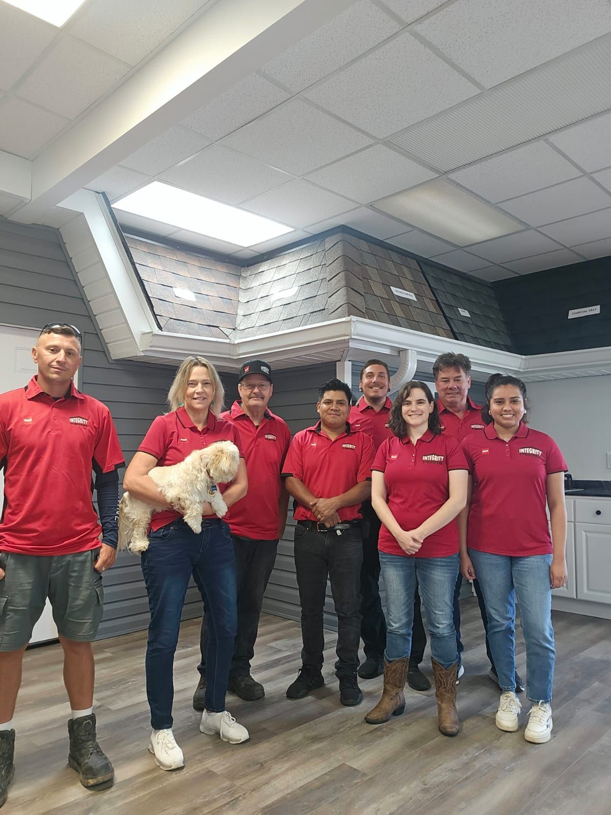 A group of people standing next to each other in a room with a dog.