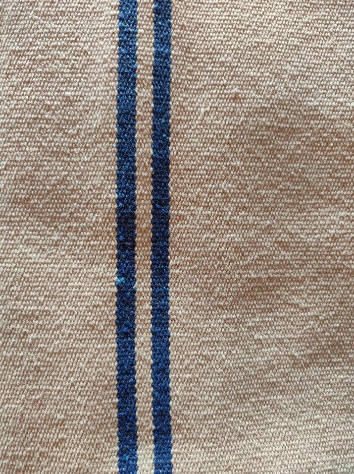 Tissu beige avec deux rayures bleues verticales.