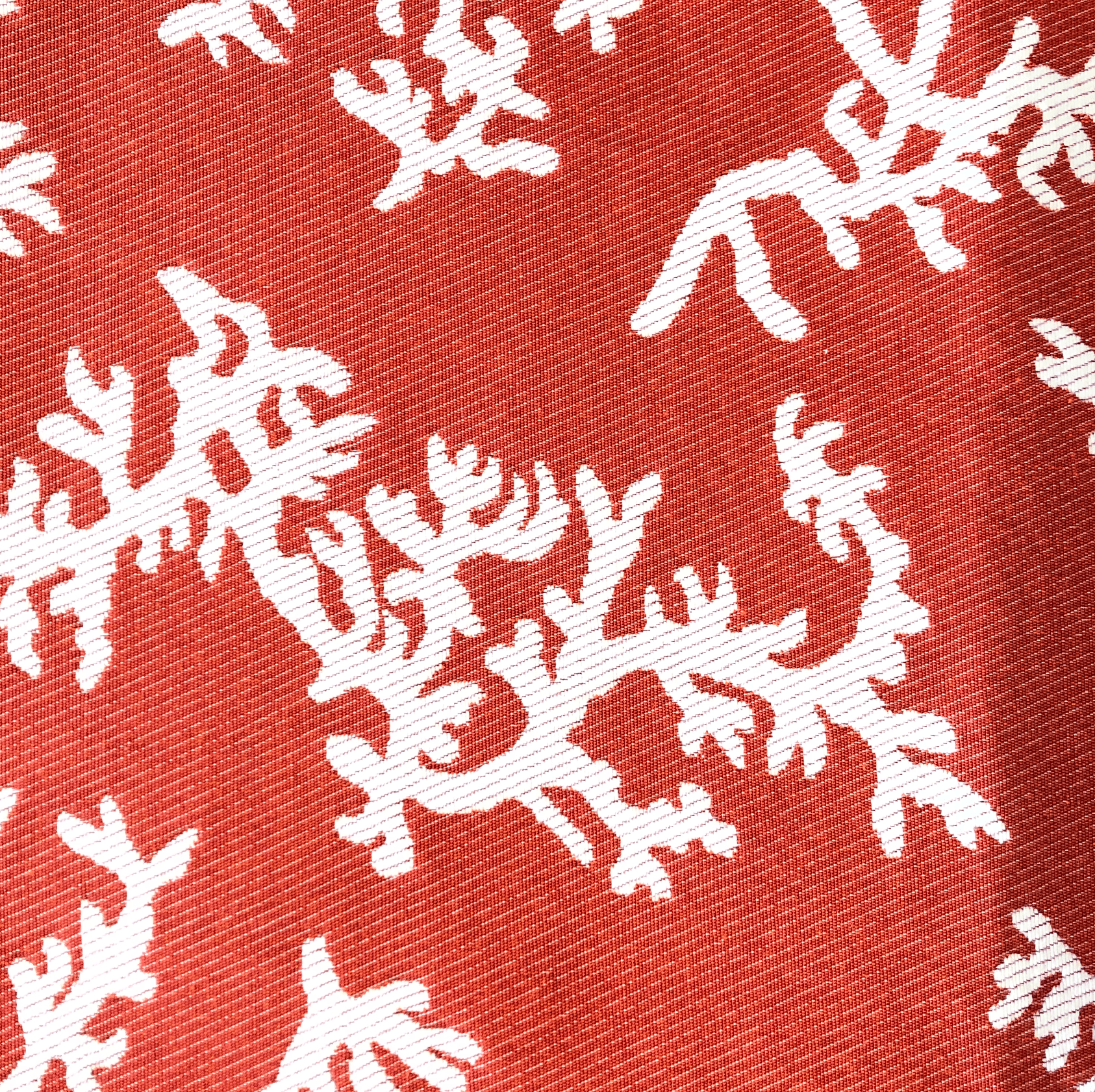 Motif corail blanc sur un tissu rouge-orange.