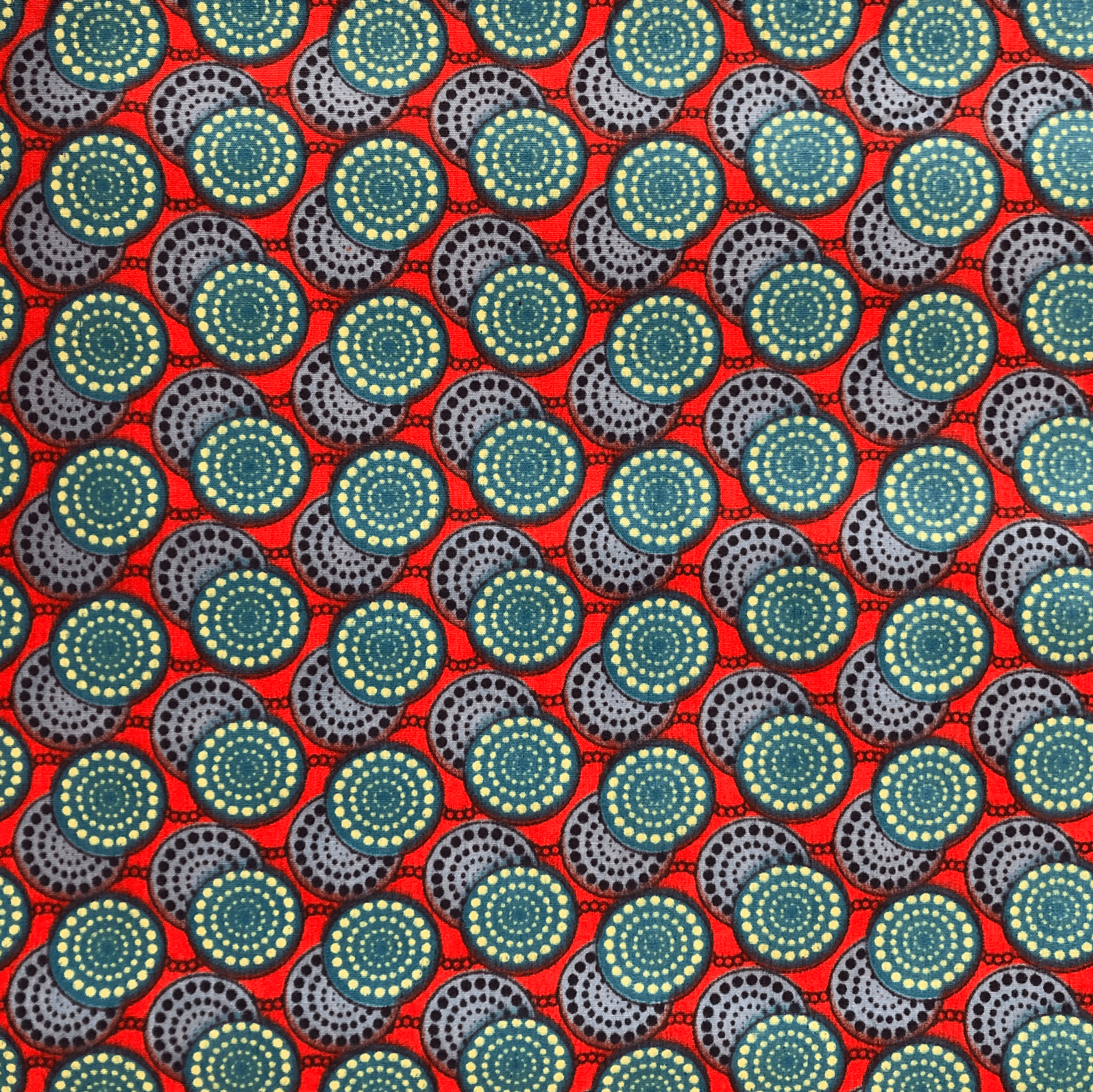 Tissu rouge avec un motif répétitif de cercles concentriques bleu sarcelle, gris et jaune.