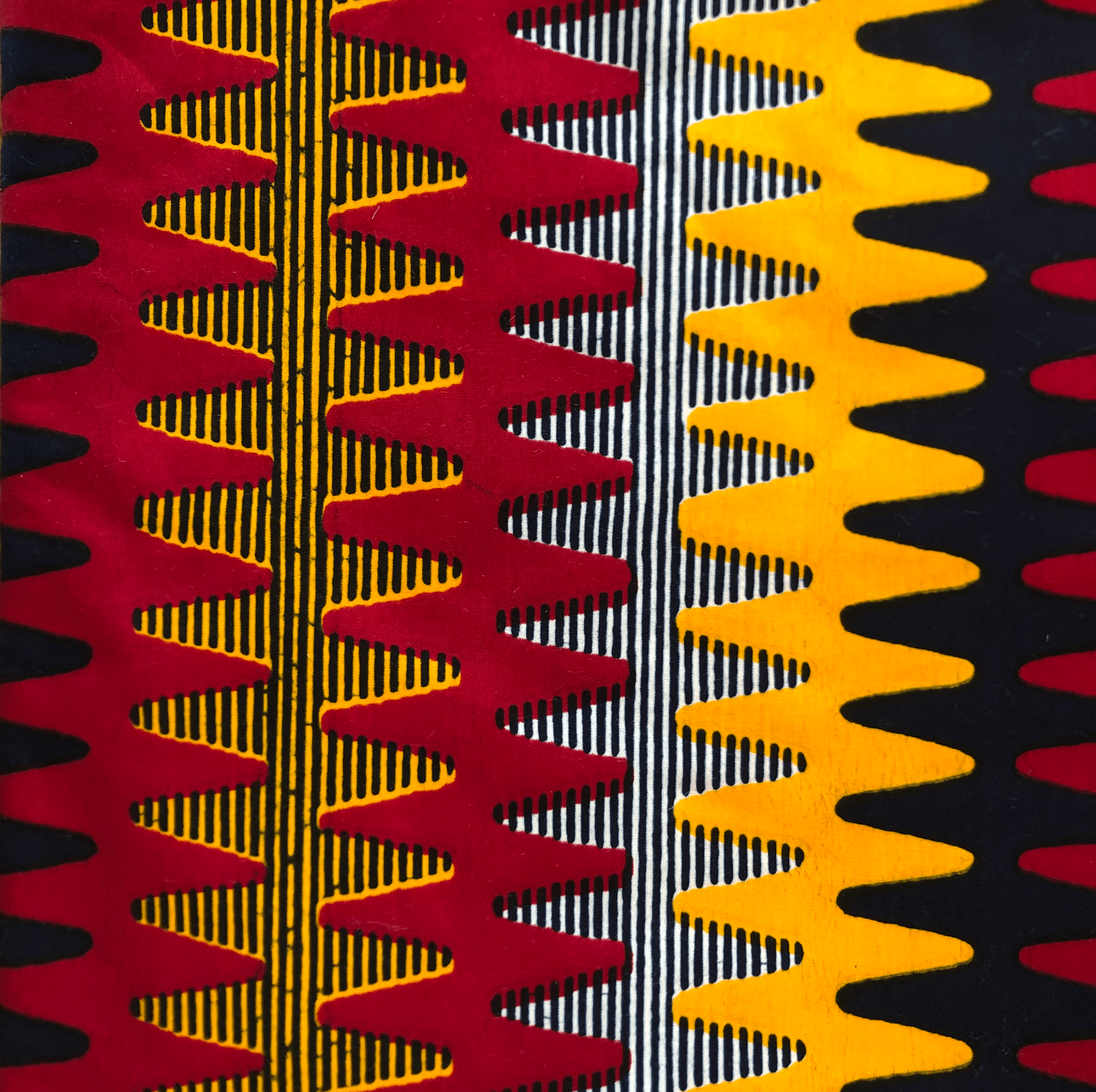 Tissu à motifs colorés avec des rayures en zigzag rouges, jaunes, noires et blanches.