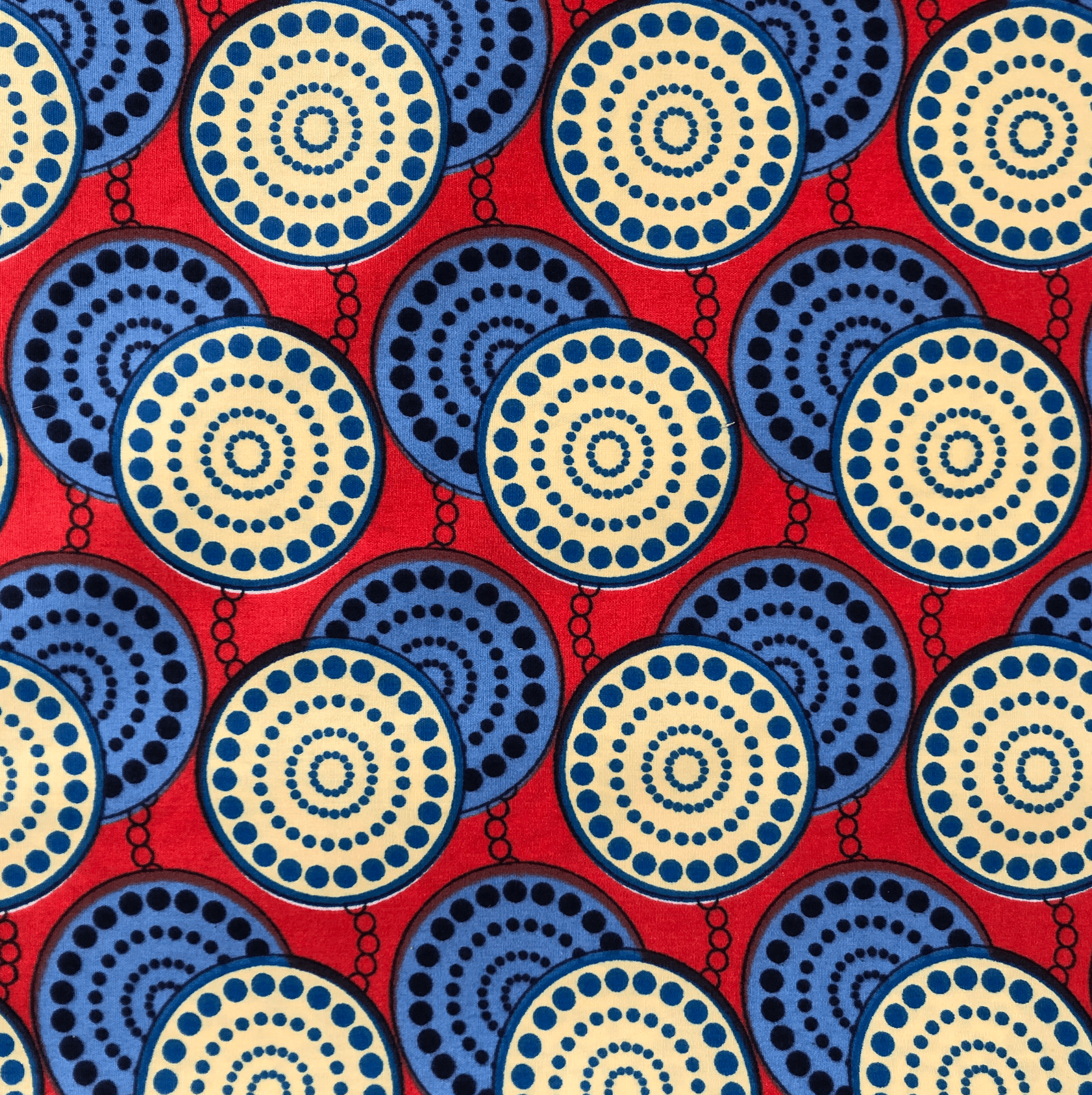 Tissu rouge avec un motif répétitif de cercles bleus et crème avec des détails à pois.