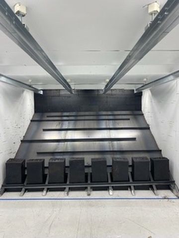 Indoor shooting range with a black sloped bullet trap and a row of target blocks on the floor.