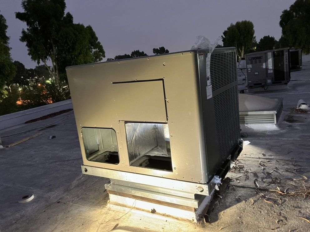 HVAC unit on a rooftop, illuminated by a light.