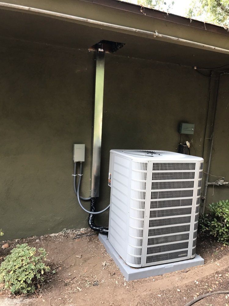 Air conditioning unit outside a building with a vent.