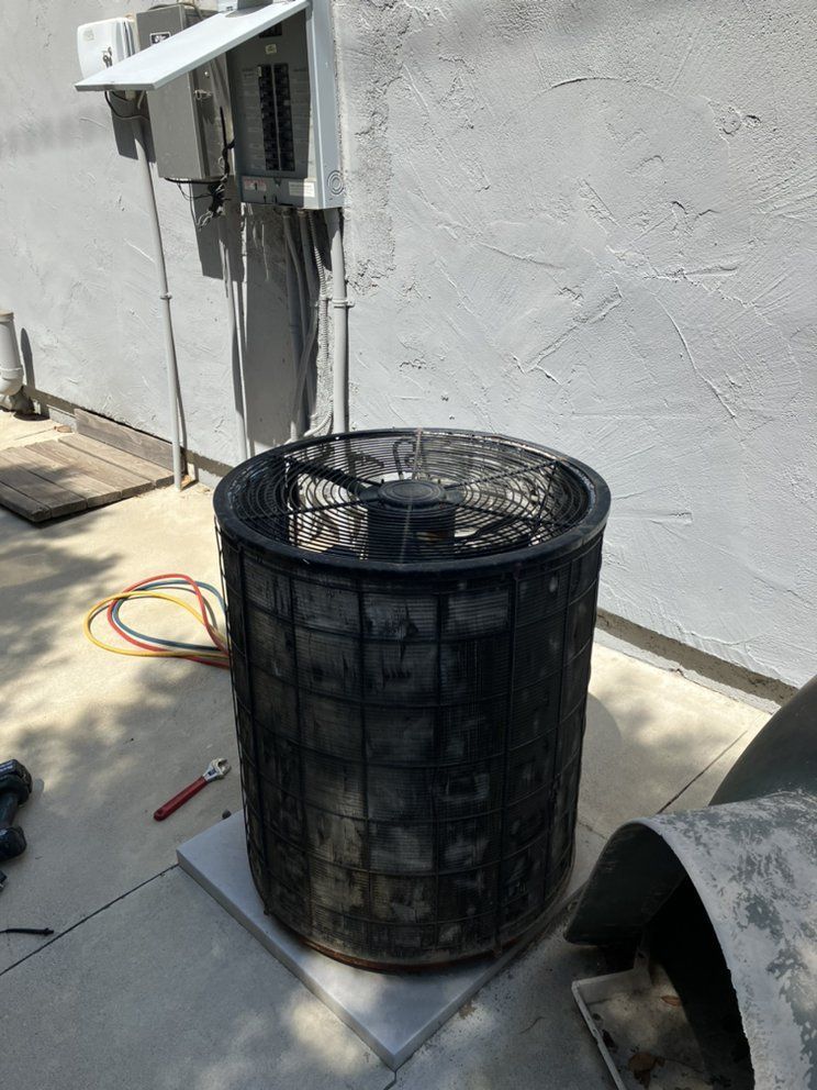 Air conditioning unit with protective cage against a concrete wall.