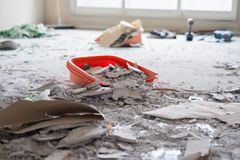 A bucket of concrete is sitting on the floor in a messy room.