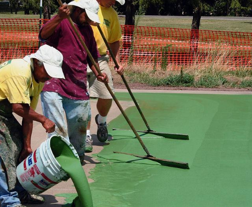 “Crew pouring and spreading green court coating evenly across the surface during a court builder service in Tucson, AZ”