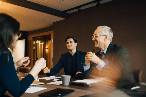 A group of people are sitting around a table having a meeting.