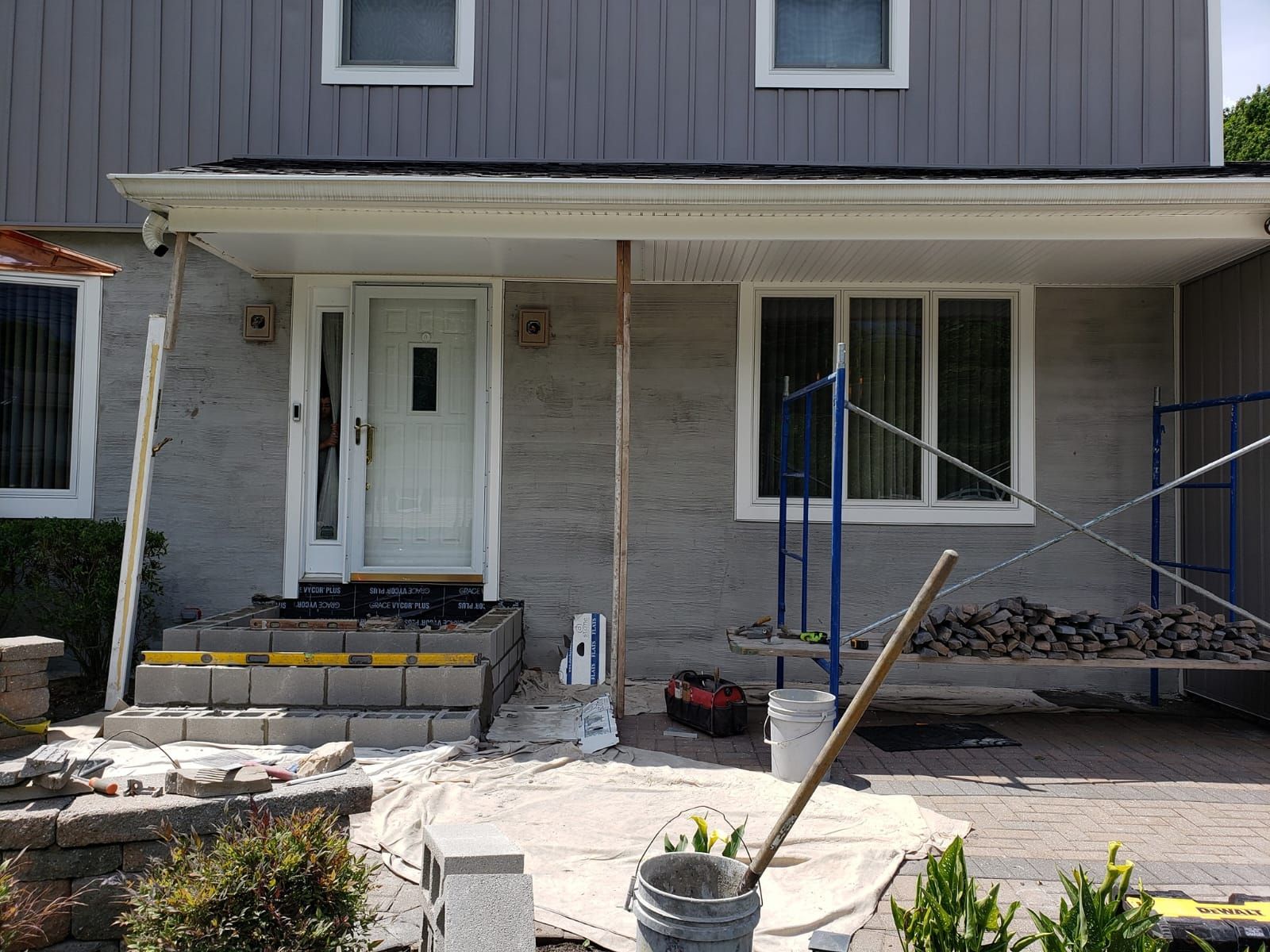 Wooden deck with white railing next to a house with gray siding. Trees and a patio umbrella are visible.