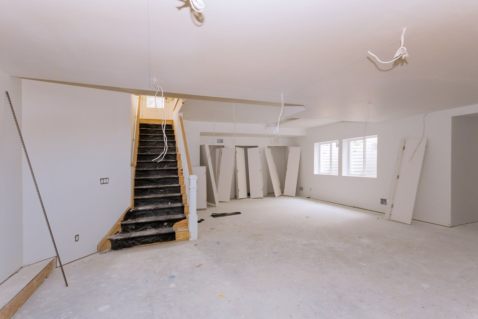 Unfinished basement space with drywall panels and exposed wiring during interior remodeling.